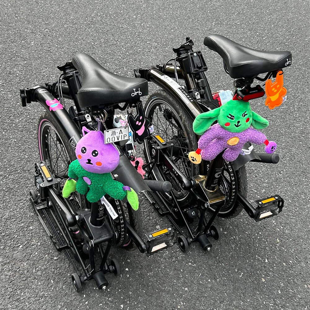 Two adorable foldable bikes each adorned with colorful plushies one purple cat and one green bunny look ready for a fun adventure